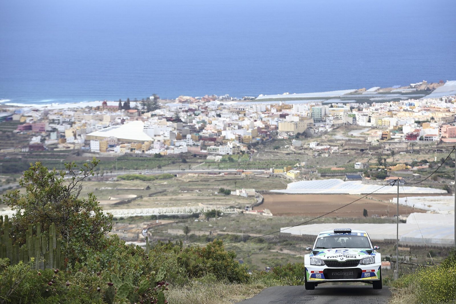 Škoda Fabia de rally subiendo una carretera con un pueblo costero al fondo, Rally Islas Canarias 2019